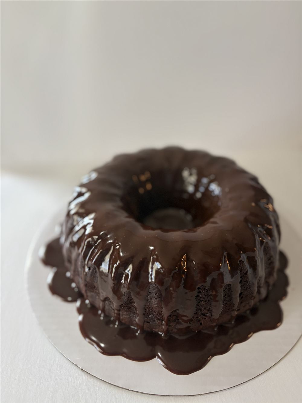A full size chocolate bundt cake under a glossy ganache