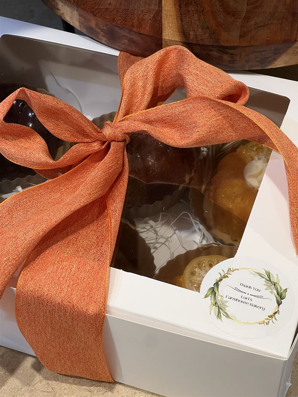 A white bakery box of mini bundt cakes tied with an orange ribbon